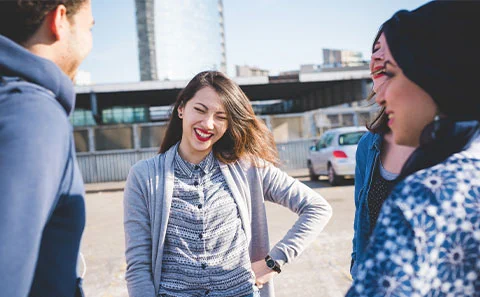 young adults stood in circle smiling and laughing