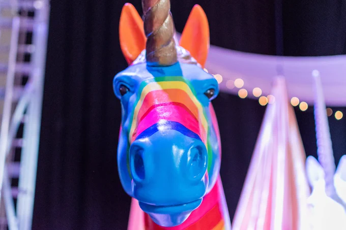 a brightly coloured unicorn looks into the lens
