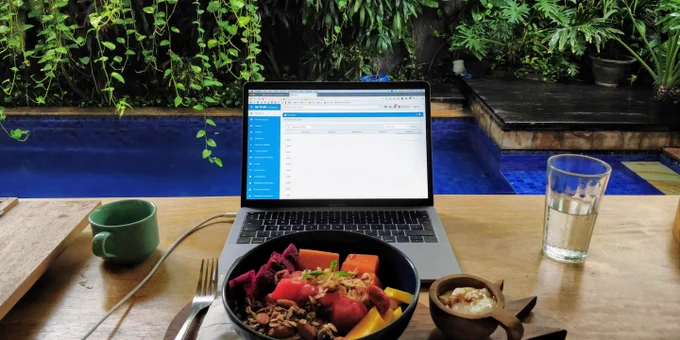 a laptop with a fruit bowl and a swimming pool in the background