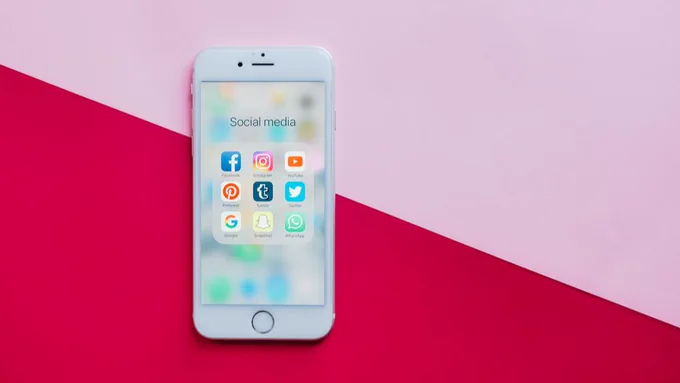An iPhone screen displaying different social media apps in a folder titled 'social media'