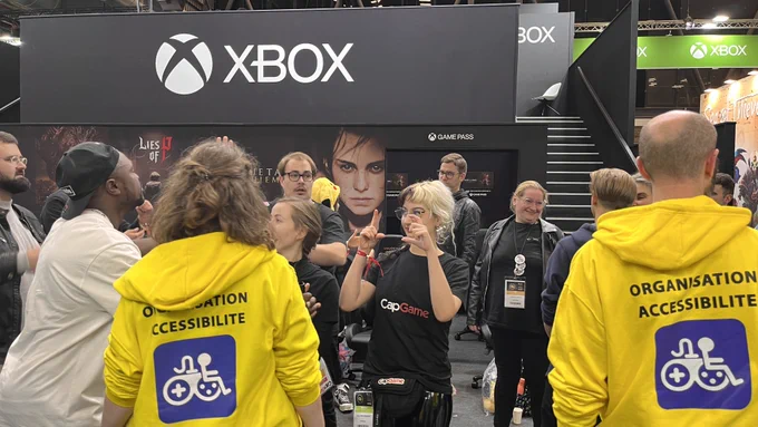 Les deux organisateurs et organisatrices de dos avec leur sweat "organisation accessiblité" en jaune sur le stand XBOX