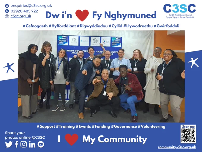 A photo of the Cardiff Third Sector Council Team surrounded by a banner with the C3SC details on, and 'I heart my community' in Welsh and English.