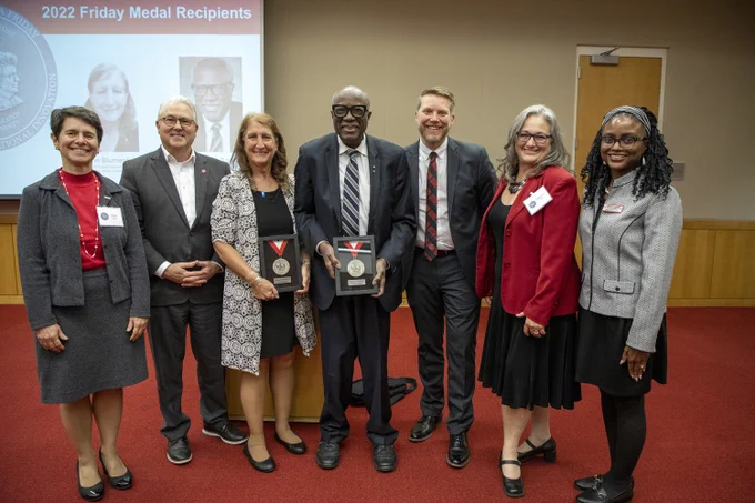 Posed photo of Friday Medal winners Joann Blumenfeld and Dr. James A. Banks holding their Friday Medal awards with (from L to R) Dean Paola Sztajn, Chancellor Randy Woodson, Shaun Kellogg, Hollylynne Lee and Callie Edwards on either side of them. 