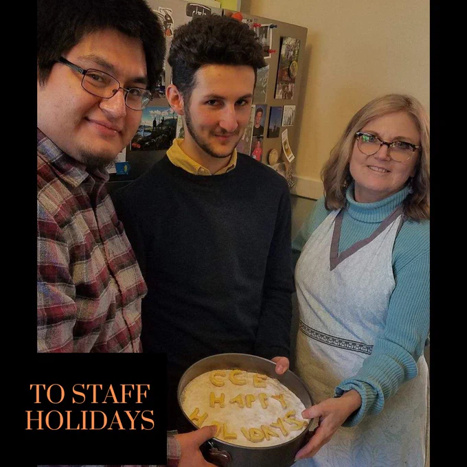 Two young men and one woman stand next to each other holding a pie which has letters on it spelling: CCE Happy Holidays. Text reads: To staff holidays.
