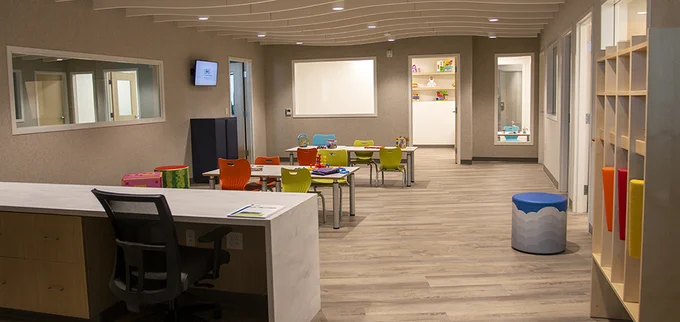 A classroom setting with a minimalist, contemporary style has brightly colored chairs and stools.