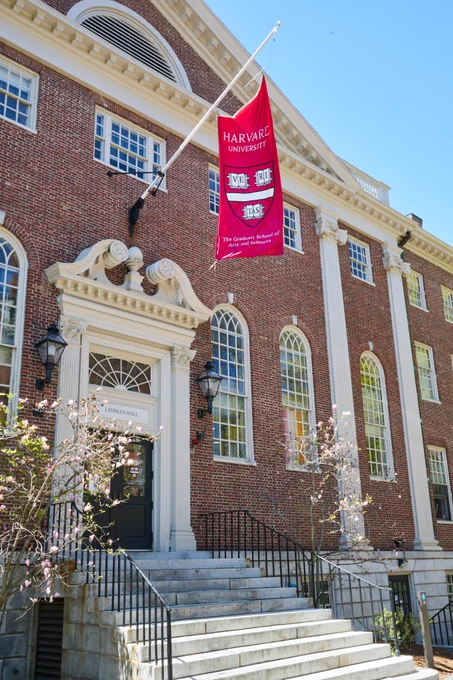 The exterior of The GSAS Student Center at Lehman Hall with crimson red GSAS flag hanging above door   stairs.