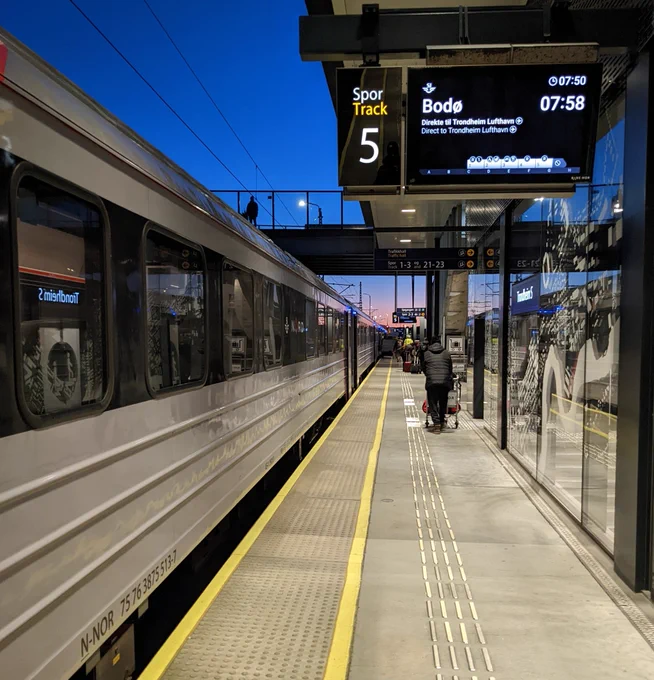Train standing at Trondheim Station with sunrise in background 
