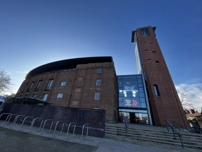 The outside of a theatre made of red bricks and a tall tower