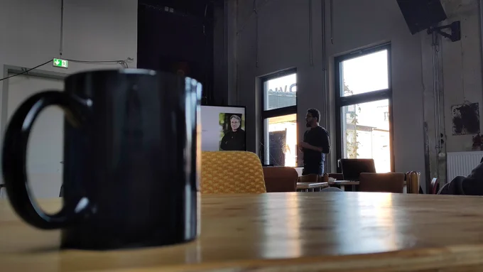 Person hält Vortrag, im Vordergrund ist eine Tasse.