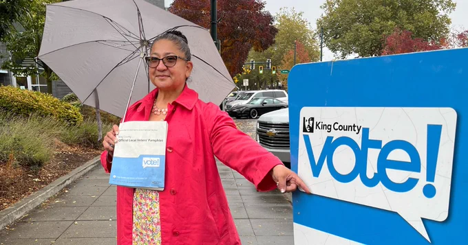 School Board Director Angelica Alvarez pointing to "vote!" on drop box.