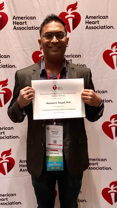 Dr. Manasa Nayak stands holding a certificate from the Council on ATVB indicating his recipt of a Travel Grant for Early Career Investigators