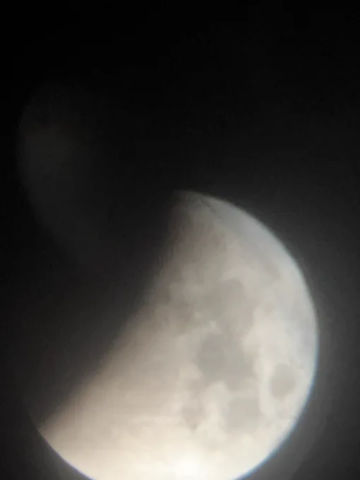 Photo through a telescope of a partially alluded moon