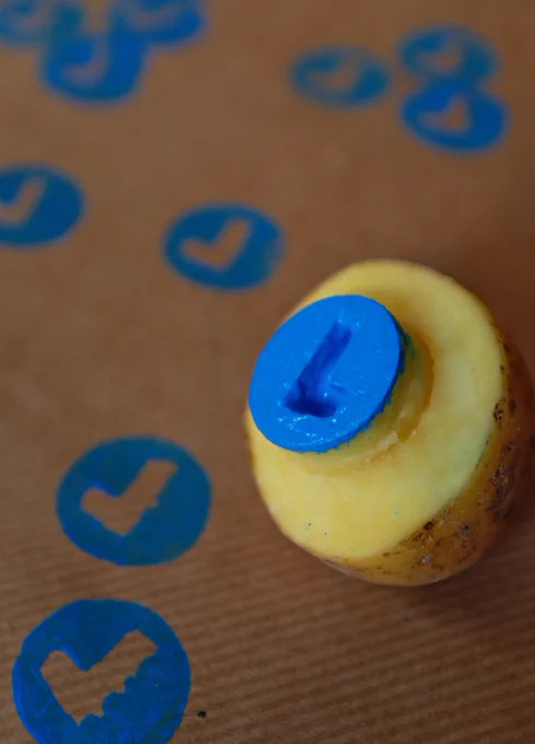 Potato stamp on brown wrapping paper with many blue, round checkmark-prints