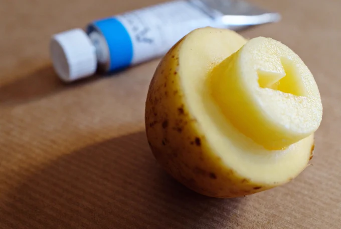 half a potato made into a checkmark-stamp. Tube with blue paint in the background