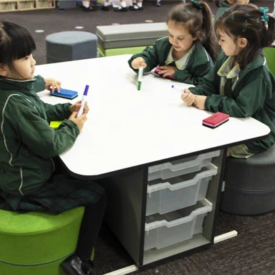 3 students sitting at a table that has built-in storage underneath