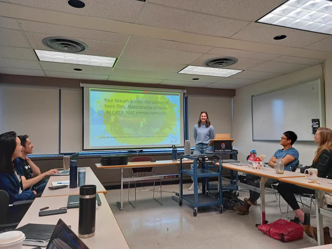 Emma standing next to a projector screen with her title slide about Horn flys