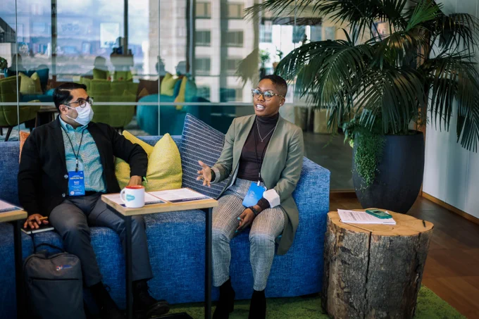 Two people sitting on a blue couch, one person is speaking