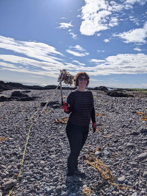 Kelly-Ann holding up a pike of wet wipes found on a beach clean using a litter picker on a sunny day