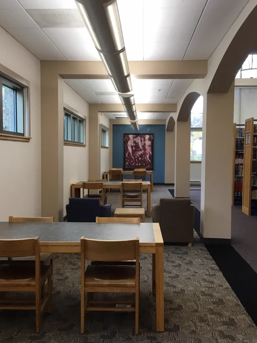 Freshly painted study tables area of the library with a blue wall alcove. Art work is hung in the center of the alcove.