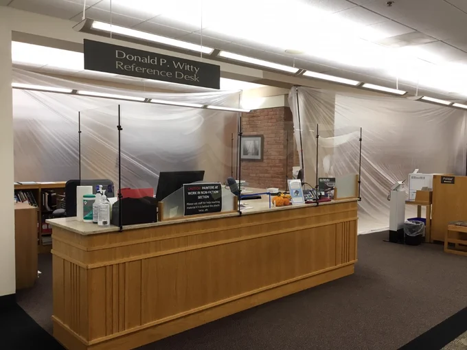 Reference desk with plastic tarps hanging behind the desk.
