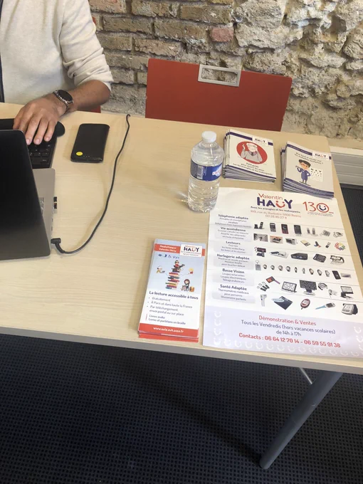 Une table avec de la documentation de l’AVH (dépliant médiathèque, affiche matériel spécialisé, petit guide pour ouvrir les yeu ….