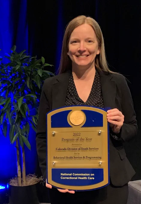 CSU social work Ph.D. student and Director of the Colorado Division of Youth Services, Ashley Tunstall, holding the award that DYS received from the national commission on correctional healthcare. 