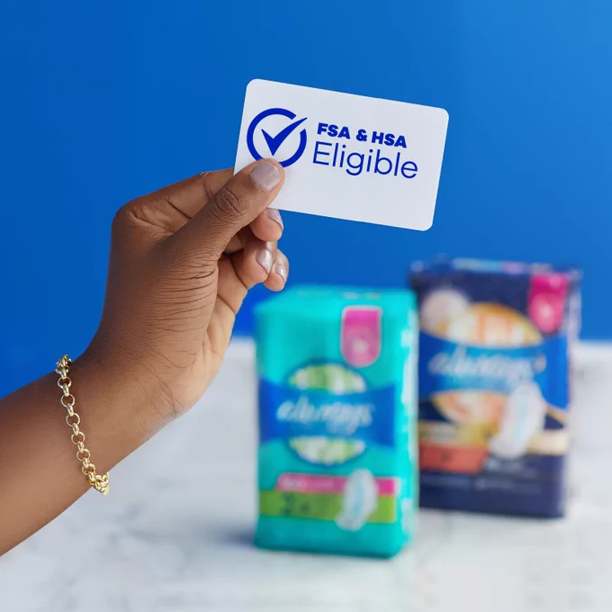 A hand holding a card with a checkmark, reading “FSA & HSA Eligible” with two packs of Always pads in the background.