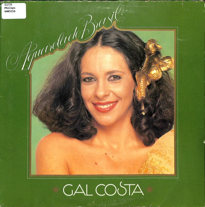 Cover of Aquarela do Brasil has a green frame with Gal Costa in the middle. There is a large golden bow on one side of her curly shoulder-length hair and she is wearing a one-shouldered gold dress.