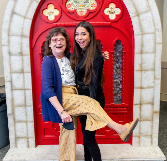 Girl hugging her mentor with her leg up laughing