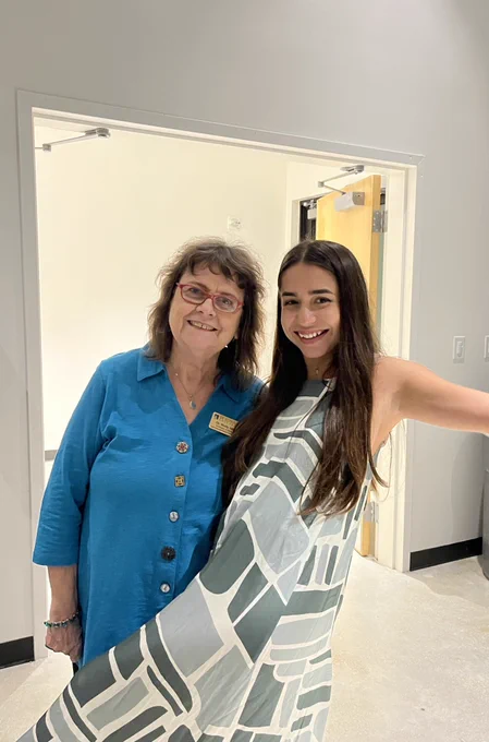Girl hugging her mentor with her leg up laughing