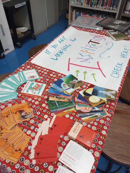 Table with a sign saying "If you are looking for inspiration, check here!", with a Writer's Emergency Pack of Cards, image cards, and picture books.