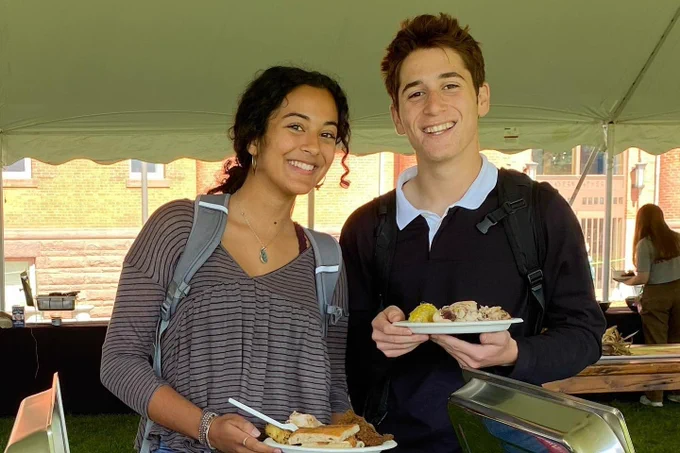 two smiling guests attending an Eat Local Challenge tent event, holding their 100% local meals