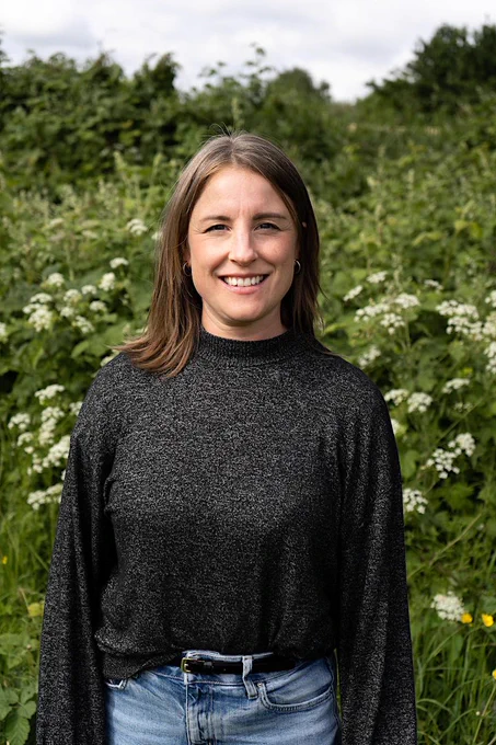 Anna Parkin, speaker and panelist at the November ShfWIT event, standing in a field of wild flowers.