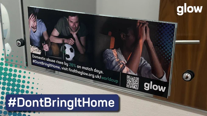 A photo of Glow's World Cup domestic abuse awareness sticker on a mirror in a toilet cubicle. The hashtag #DontBringItHome is at the bottom of the image. 