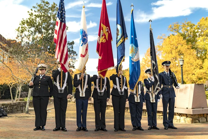 Armed service members holding flags.