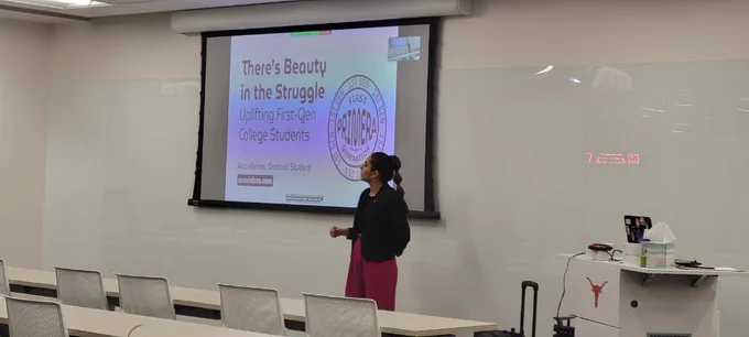 Girl in pink pants standing in front of a projector presenting her research on the first-gen community