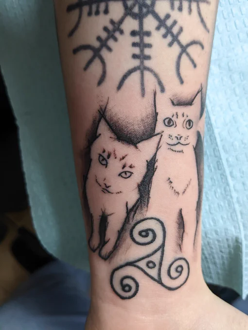 A simplistic black outline tattoo of Melon and Prim. The symbol of Freya is tattooed below them. She rode a chariot pulled by two cats.