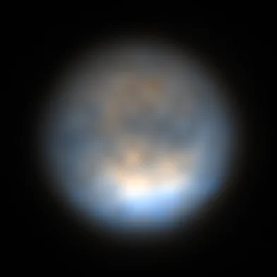 A low resolution view of Saturn's moon, Titan. Dark features stretch across the equator. The moon is more brightly illuminated at its southern pole.