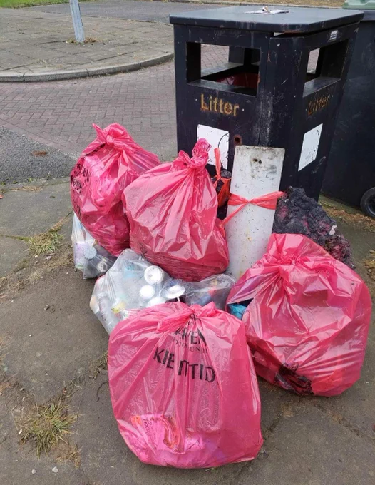 Bags of litter collected by volunteers, left by a council bin.