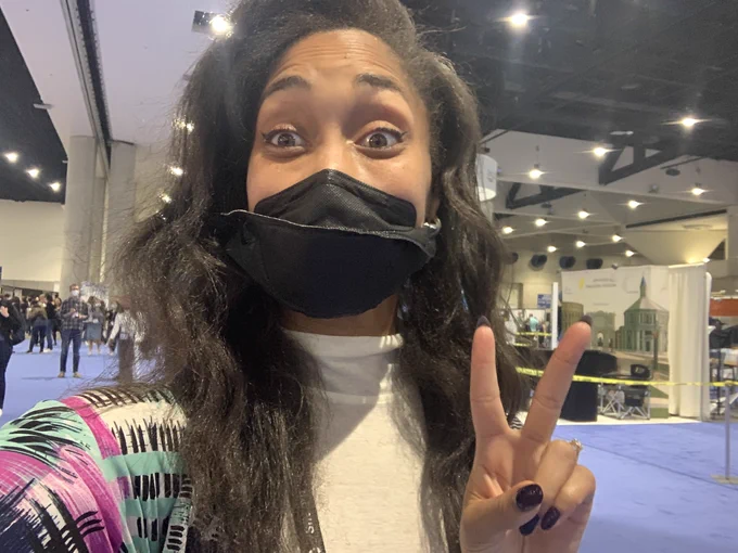 A selfie of Brielle I’m the poster hall. She is holding up two peace fingers and is smiling widely behind her mask.