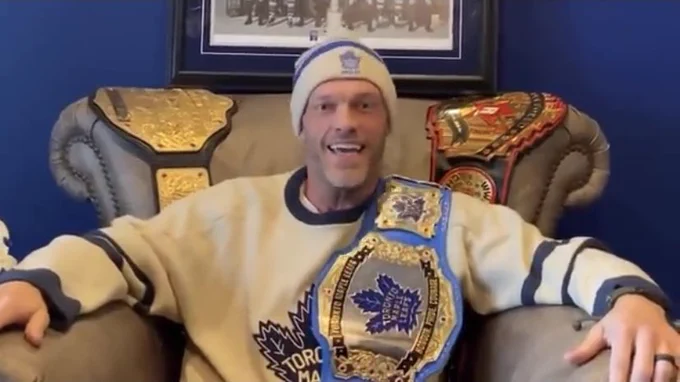 Edge in a video he made challenging Steve dangle to about who is the biggest Leafs fan, in which he is wearing a belt over his shoulder. He’s also sitting on an armchair with other championship belts behind him. He’s wearing a trial Mapleleaf sweater and toque.