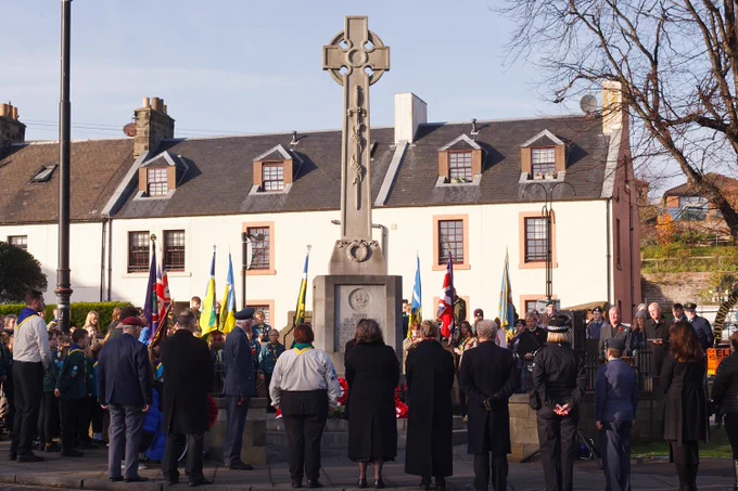 Burntisland war memorial during the service with people standing before laying wreathes