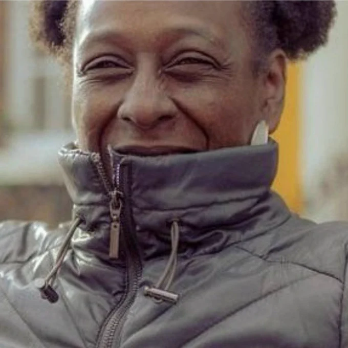 A picture of Michelle smiling and wearing a black jacket which is zipped up over her chin.