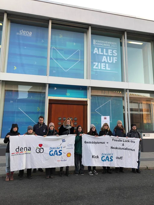 Menschen vor einem Kongresszentrum mit Bannern, auf denen steht: Gaslobbyismus = Fossile LockIns & Neokolonialismus - Kick Zukunft Gas out!