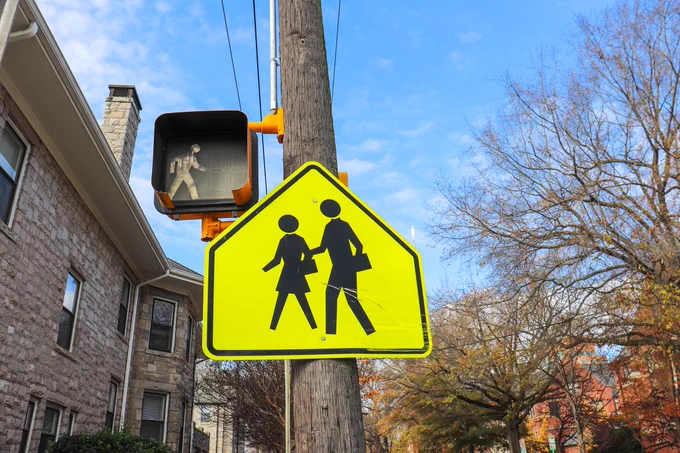 Two pedestrian signs affixed to a utility pole in downtown Raleigh. One is electronic and one is not. 
