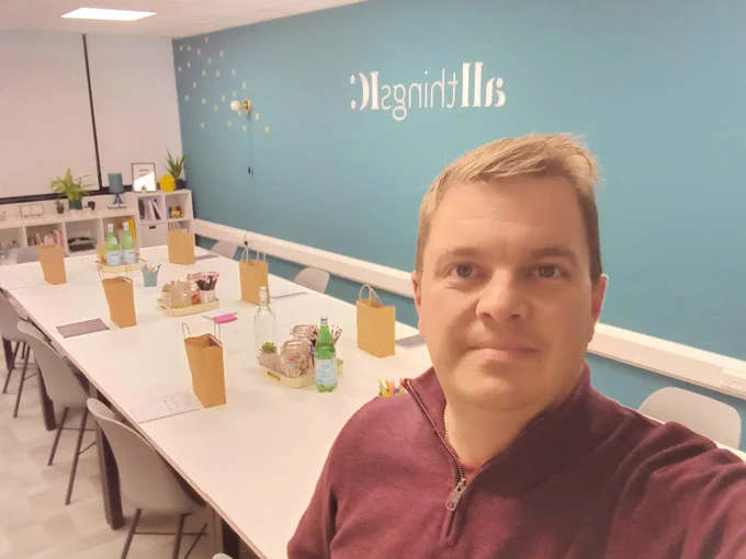 Selfie of Dan Holden at the All Things IC Hub with the tables set-up ready for attendees with brown paper goodie bags and notebooks out.