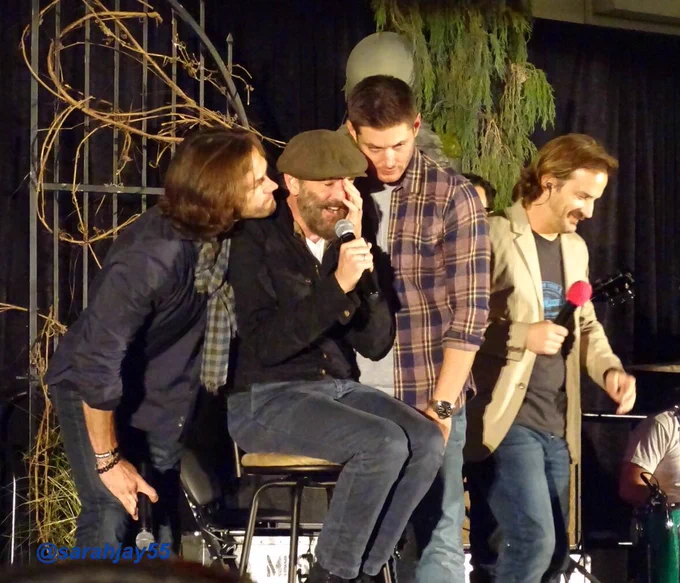 Jared and Jensen loom over Tim Omundson who is seated on stage, his hand covering half his face and closed eyes, cos he’s all overcome and honestly, fangirling a bit! Richard Speight Jr is lurking just behind jensen