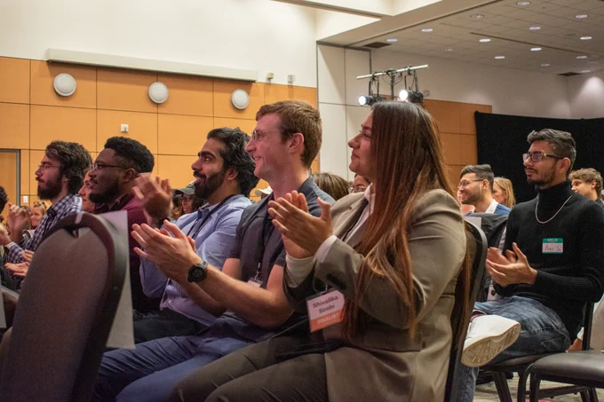 Group of students and staff clapping in the audience.