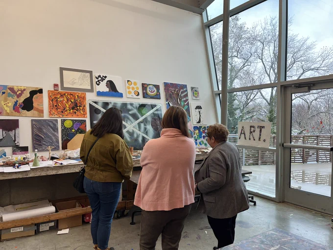 Three women looking at youth’s art