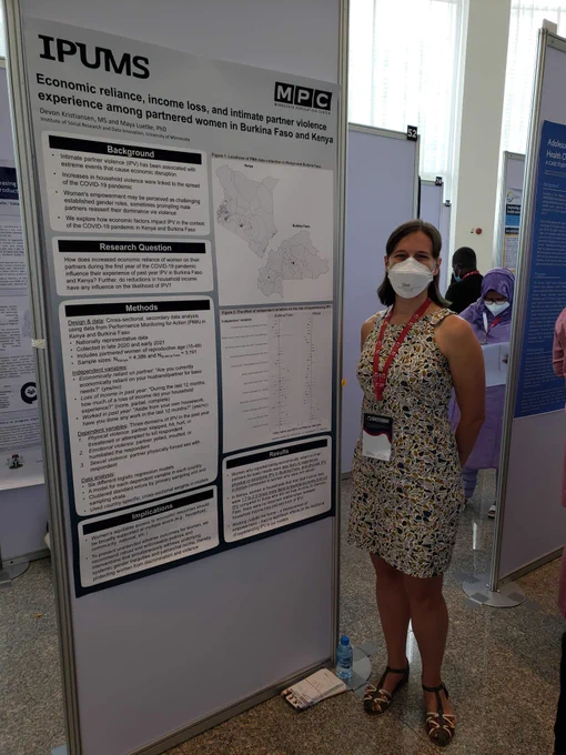 Picture of a Devon standing next to a research poster, smiling beneath the mask. 